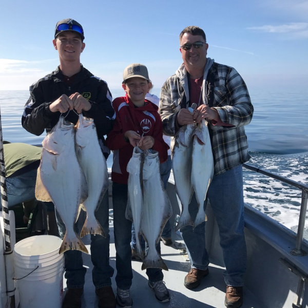 Family holding up halibut catches on fishing trip