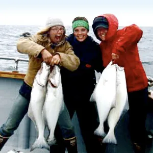 Three women holding halibut and smiling at the camera